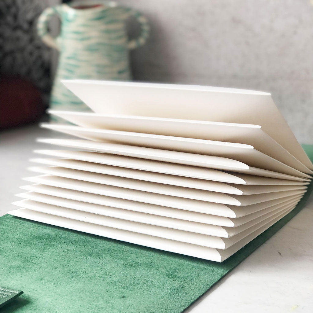 Stack of white envelopes pages in a green leather journal
