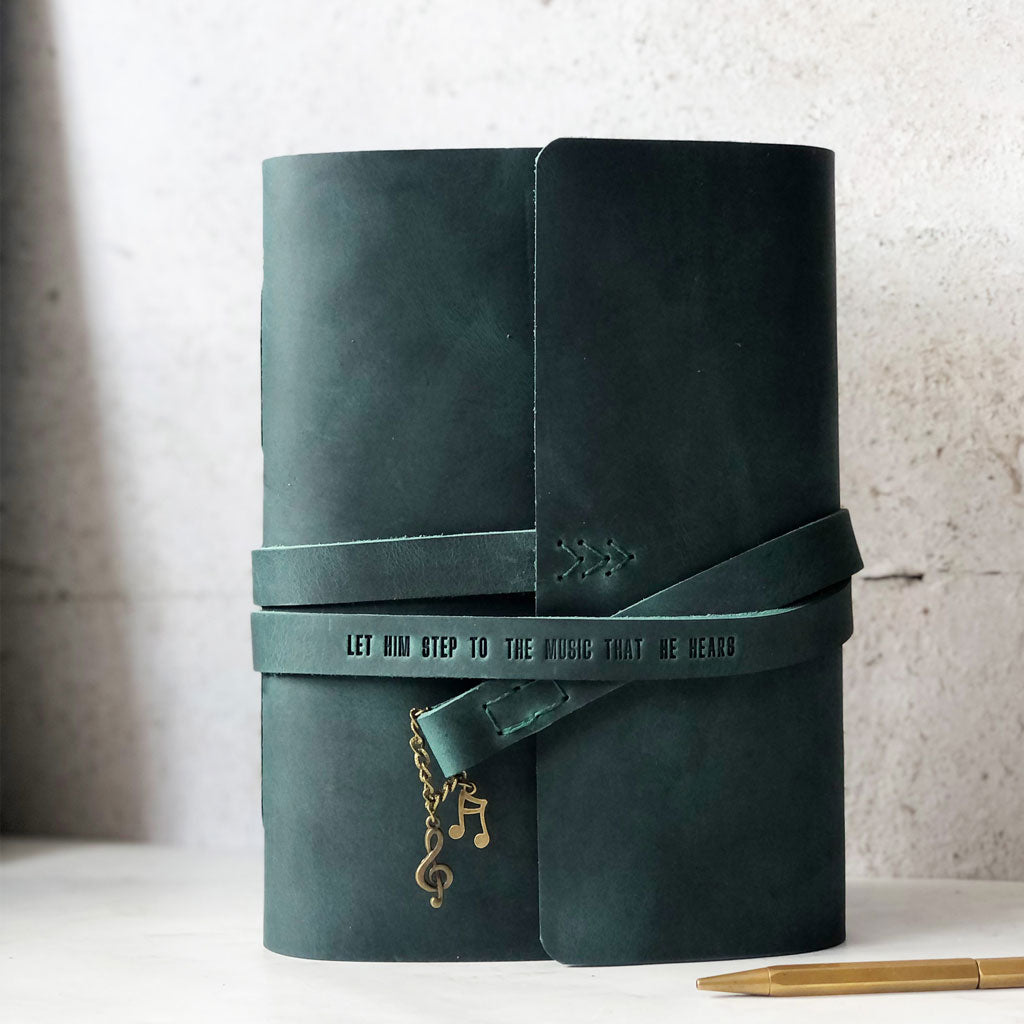 Green leather-bound notebook with custom embossed quote on strap