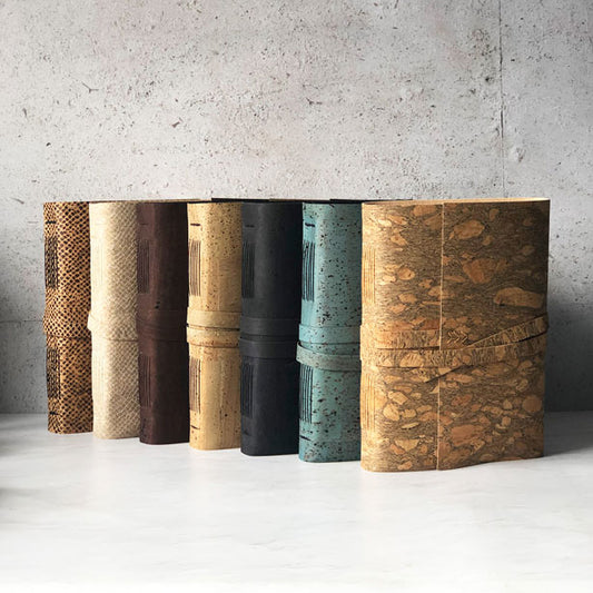 A collection of faux leather journals with cork material in various colors displayed side by side.