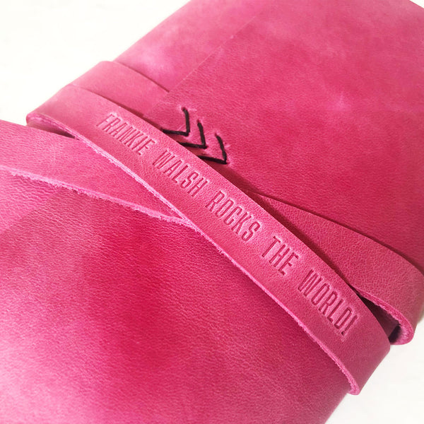 close up of pink leather journal with custom embossed quote on strap